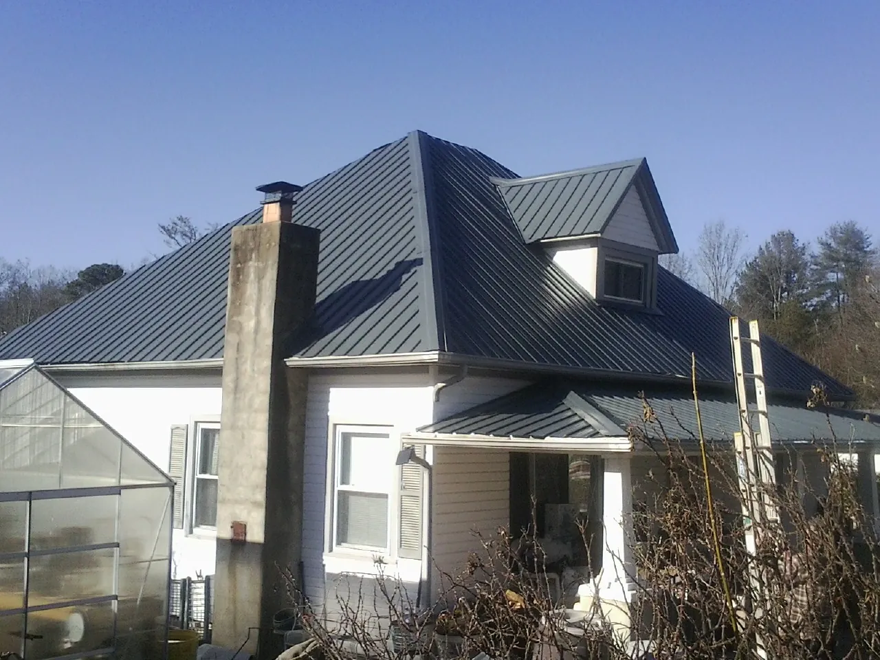 Dark blue standing seam metal roof on a white farmhouse with dormer — Slate & Tile Roof Repair by Roofing Brothers in South Hackensack
