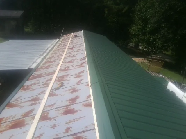 Old rusted panels beside newly installed green metal roofing — Wind Damage Roof Repair by Roofing Brothers in South Hackensack