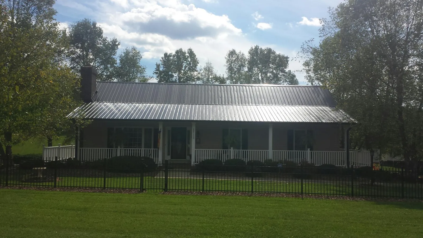Gray metal roof on a brick ranch with a full width front porch — Gutter Guard Installation work by our crew in South Hackensack
