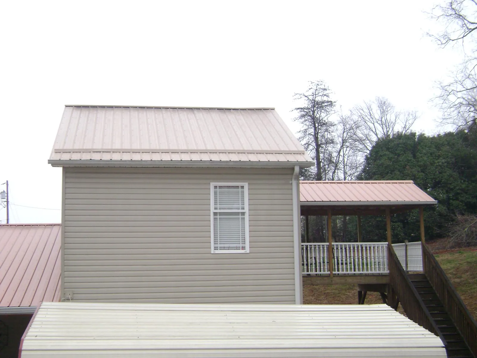 Tan metal roofs on a two story addition and attached porch, from a Roof Replacement job in South Hackensack